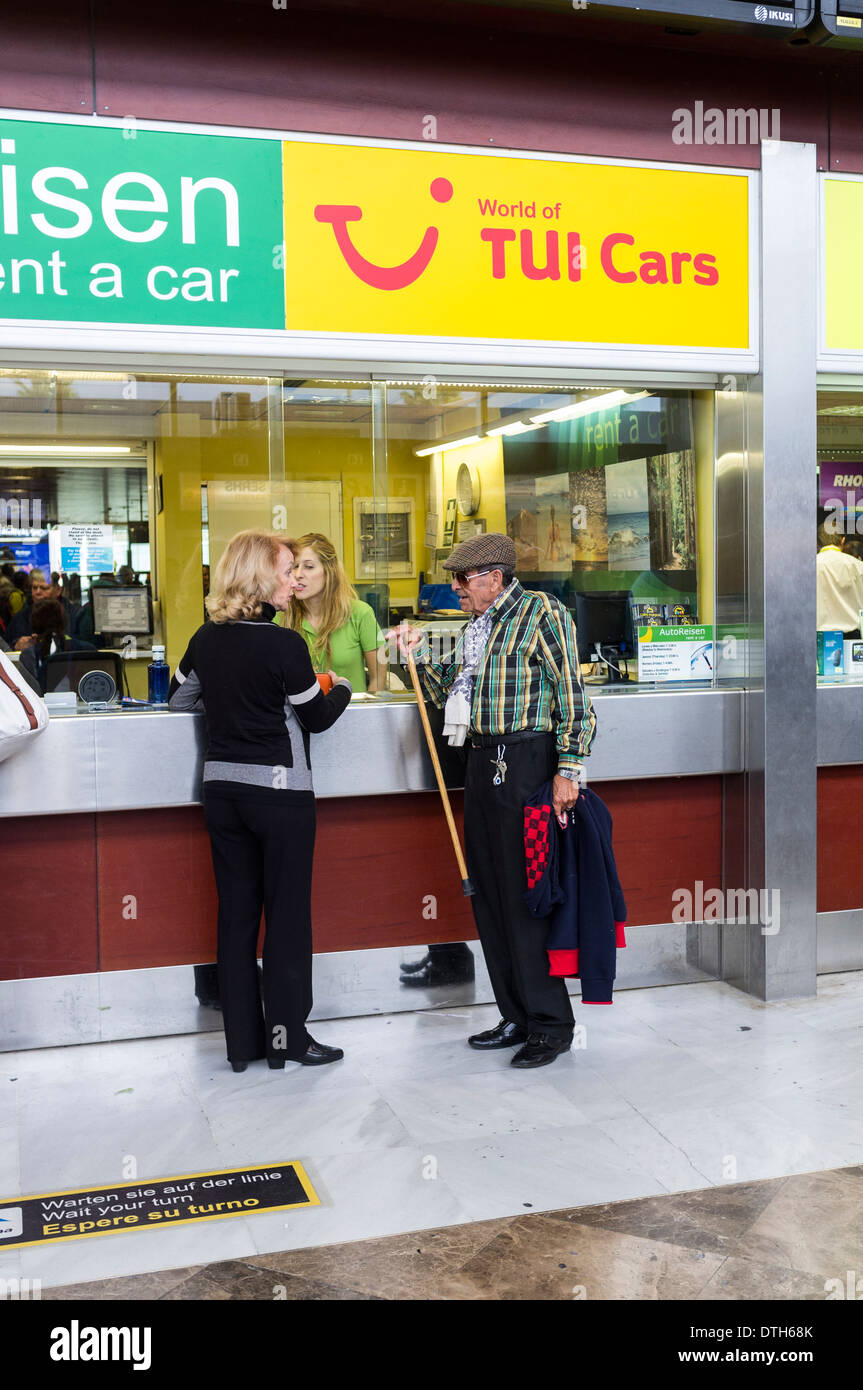 Un couple à un bureau de location de voiture dans l'aire des arrivées à l'aéroport de Ténérife Sud, îles Canaries, Espagne. Banque D'Images