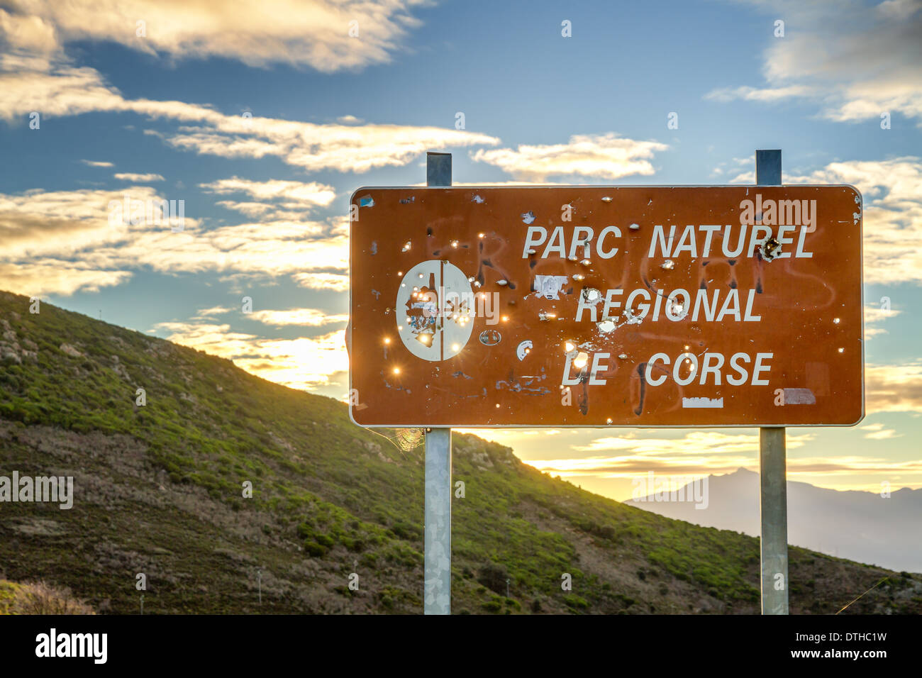 Parc Naturel de Corse panneau criblé de trous de balle du chasseur contre un soleil levant Banque D'Images