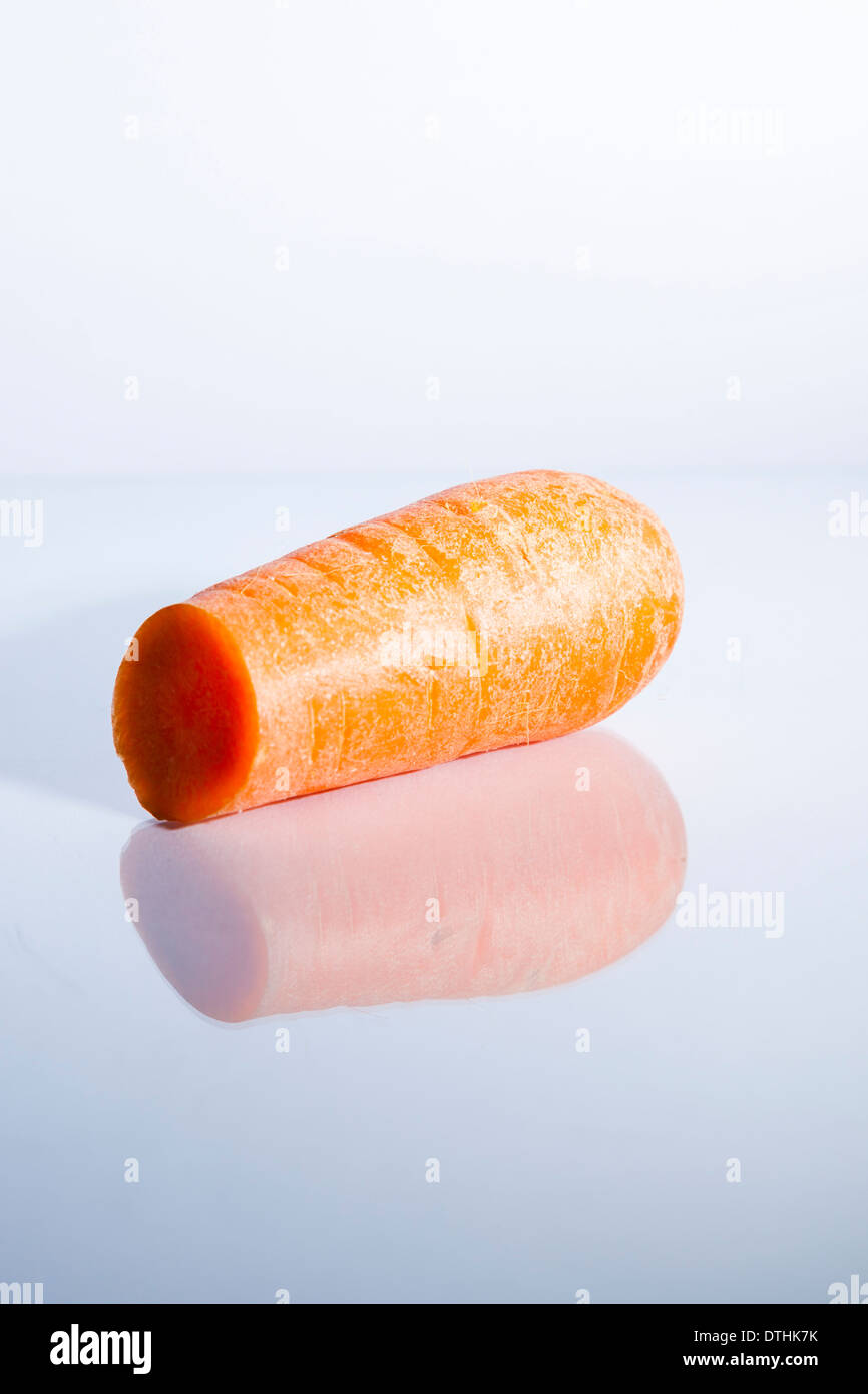 Une carotte en tranches assis sur une surface en verre blanc avec reflet Banque D'Images
