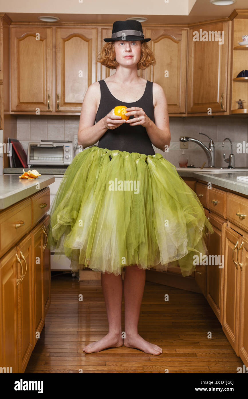 Une femme portant un tutu de ballet vert lime debout dans une position de ballet dans sa cuisine New York USA Banque D'Images