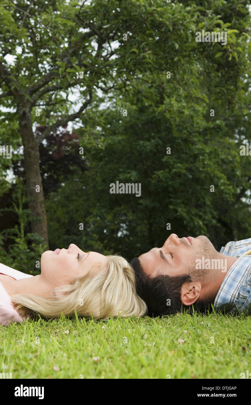 Un couple allongé sur le dos, tête de toucher sur l'herbe en Angleterre Banque D'Images