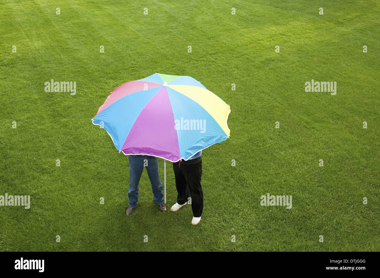 Deux personnes sous un parapluie à rayures sur une pelouse, Angleterre Banque D'Images