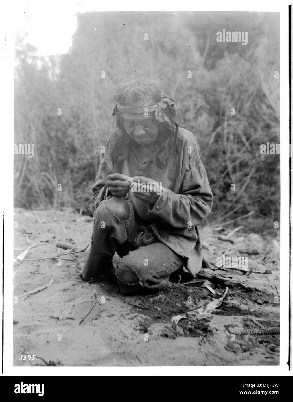 Un vieil homme indien Havasupai accroupi et roulant une cigarette, photographié vers 1900. Banque D'Images