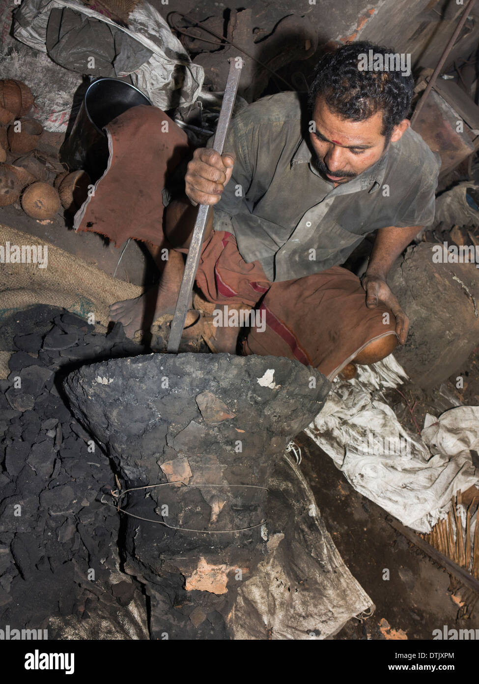 L'Inde, le Kerala, Mannar, metal foundry worker de casser le moule de cloche en bronze coulé récemment Banque D'Images