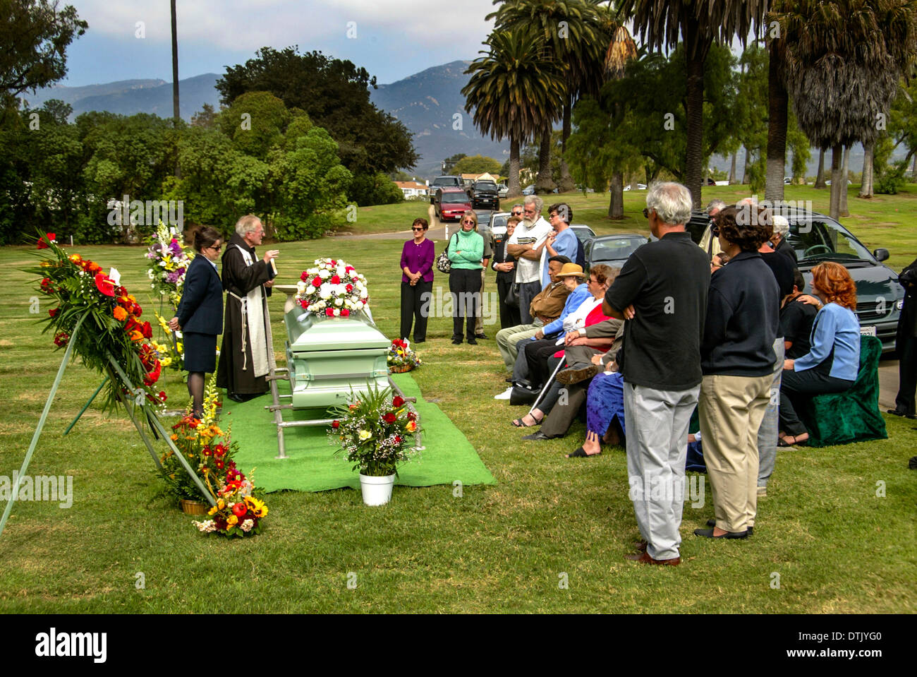 Un prêtre franciscain vêtu lors d'une inhumation dans officie Santa Barbara, CA. Remarque cercueil et fleurs. Banque D'Images