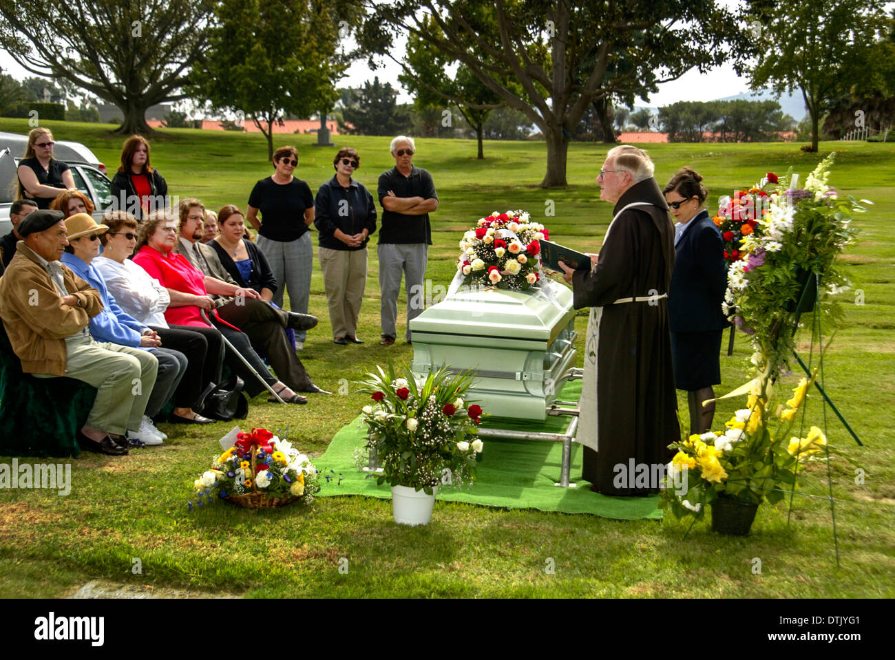 Un prêtre franciscain vêtu lors d'une inhumation dans officie Santa Barbara, CA. Remarque cercueil et fleurs. Banque D'Images