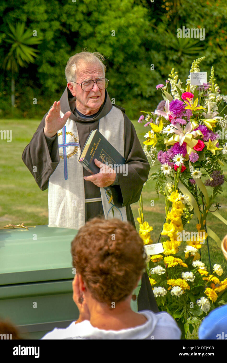 Un prêtre franciscain vêtu lors d'une inhumation dans officie Santa Barbara, CA. Remarque cercueil et fleurs. Banque D'Images