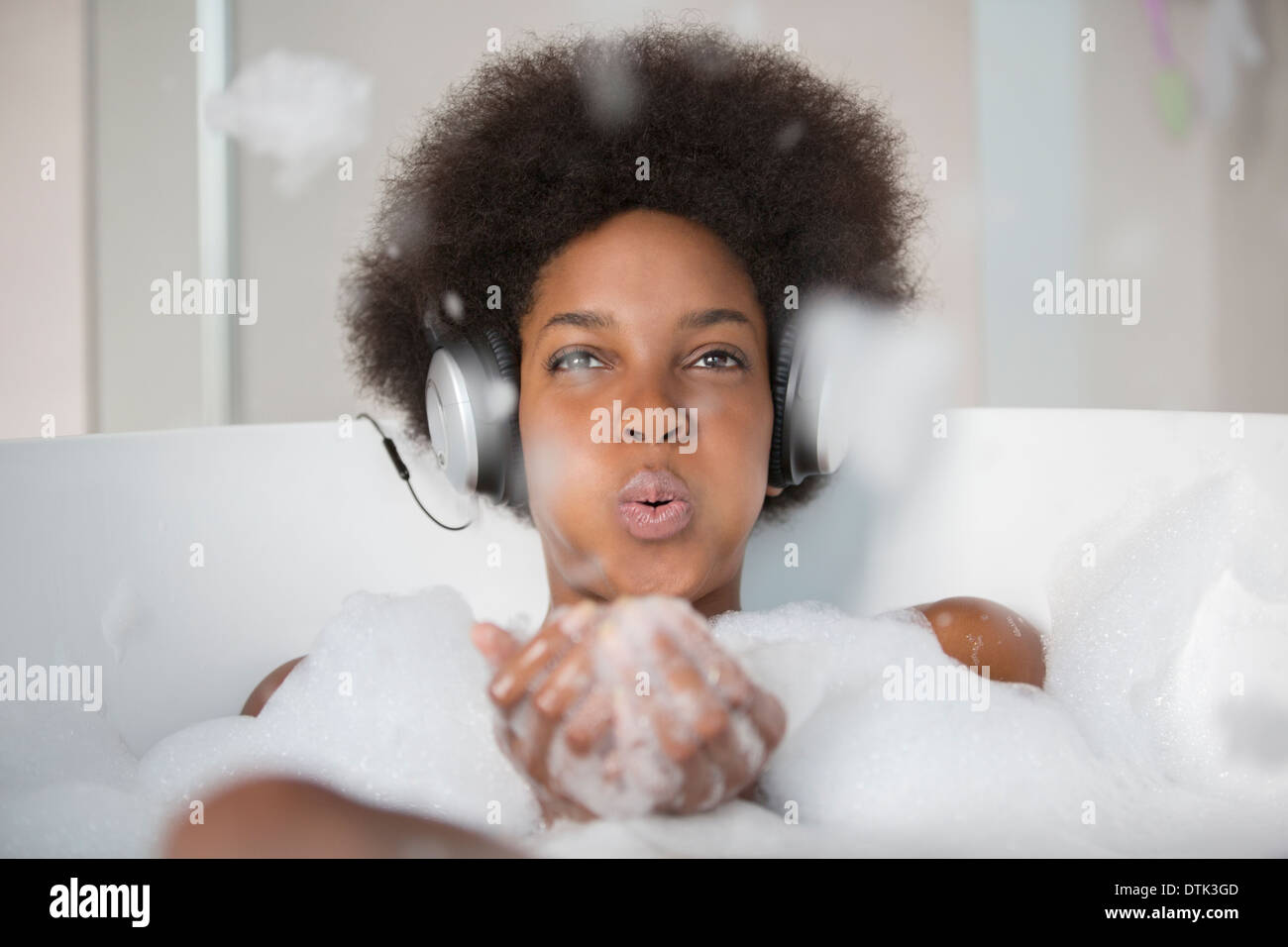 Woman listening to headphones in bath Banque D'Images