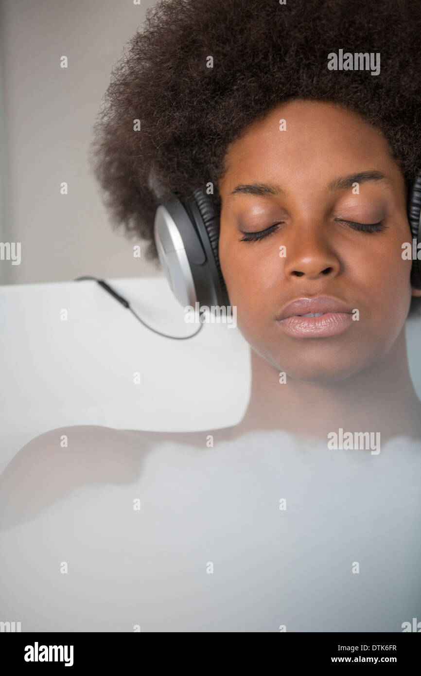 Woman listening to headphones in bath Banque D'Images