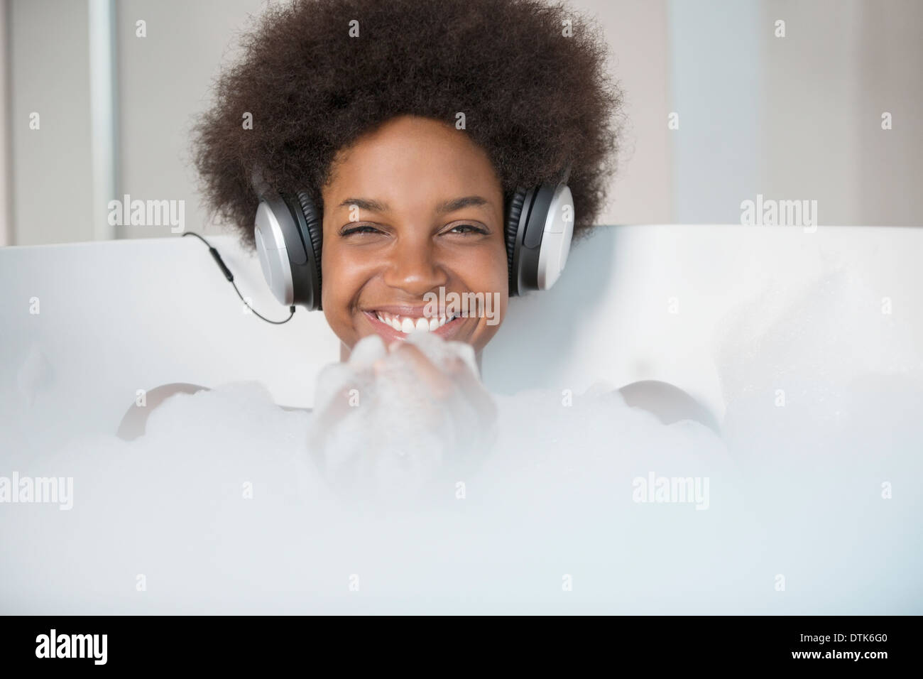 Woman listening to headphones in bath Banque D'Images