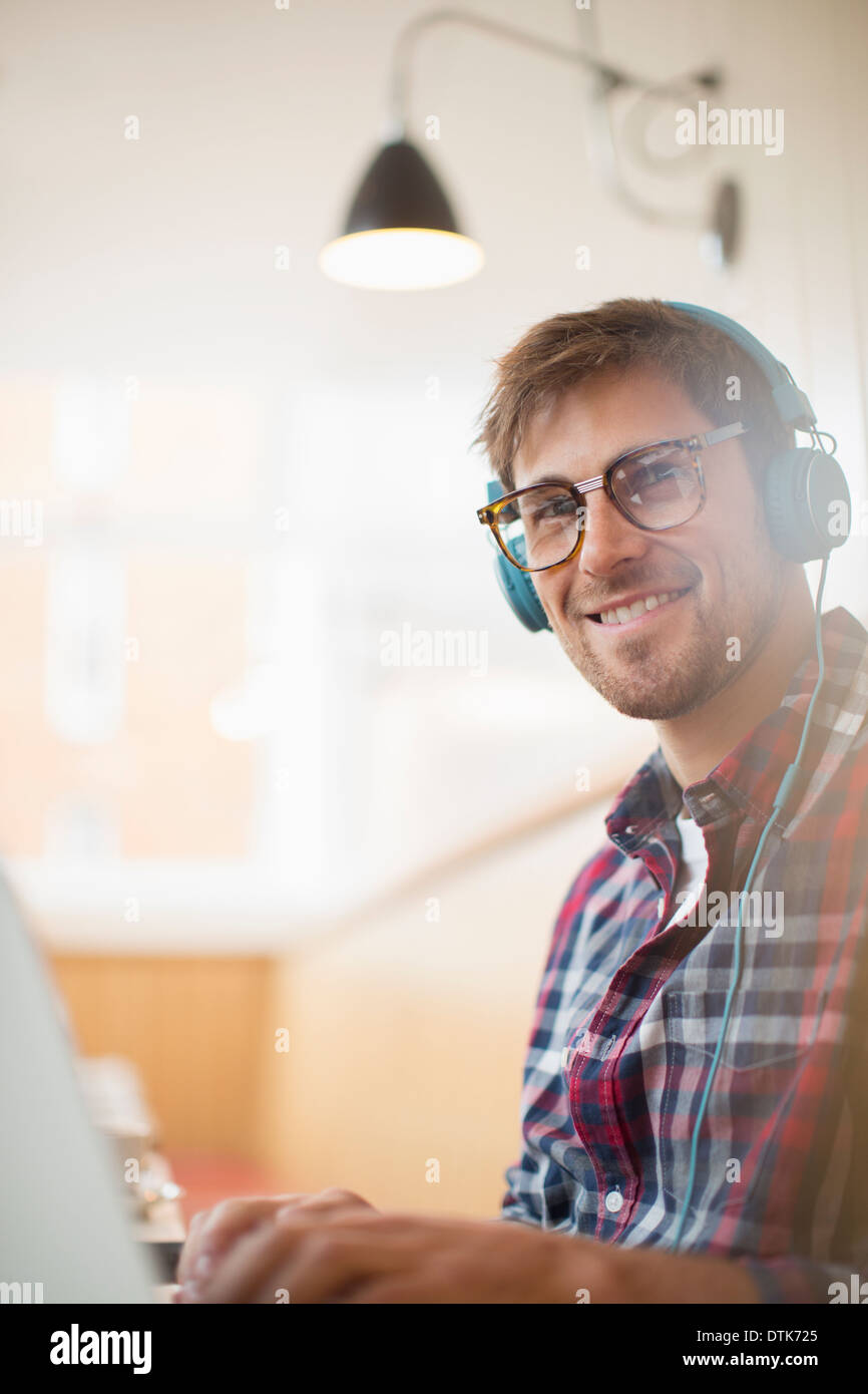 Man wearing headphones and using laptop Banque D'Images