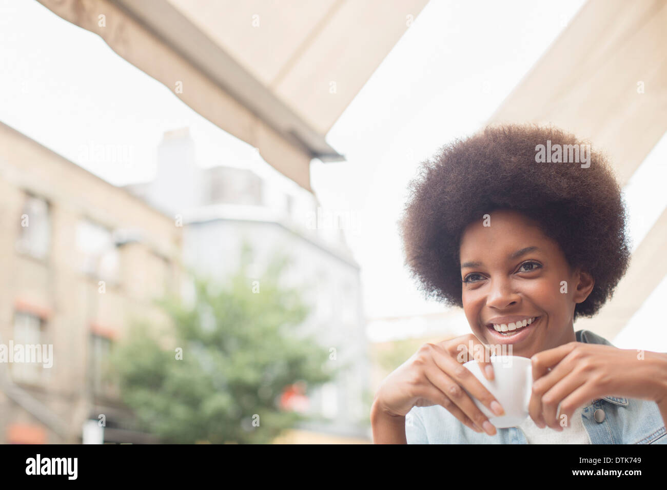 Woman drinking coffee at sidewalk cafe Banque D'Images