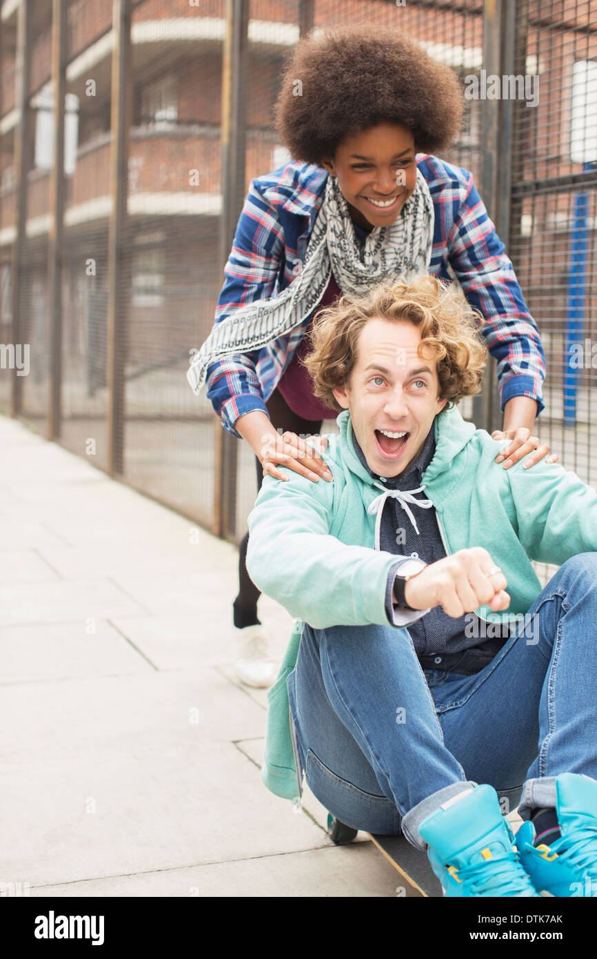 Couple playing on skateboard on city street Banque D'Images