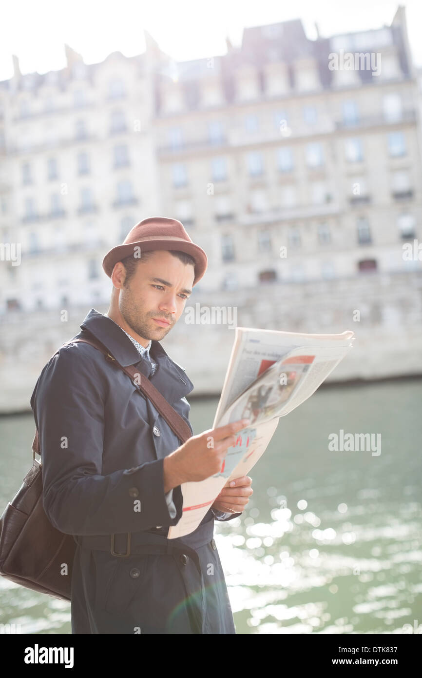 Businessman reading newspaper le long de la rivière Seine, Paris, France Banque D'Images