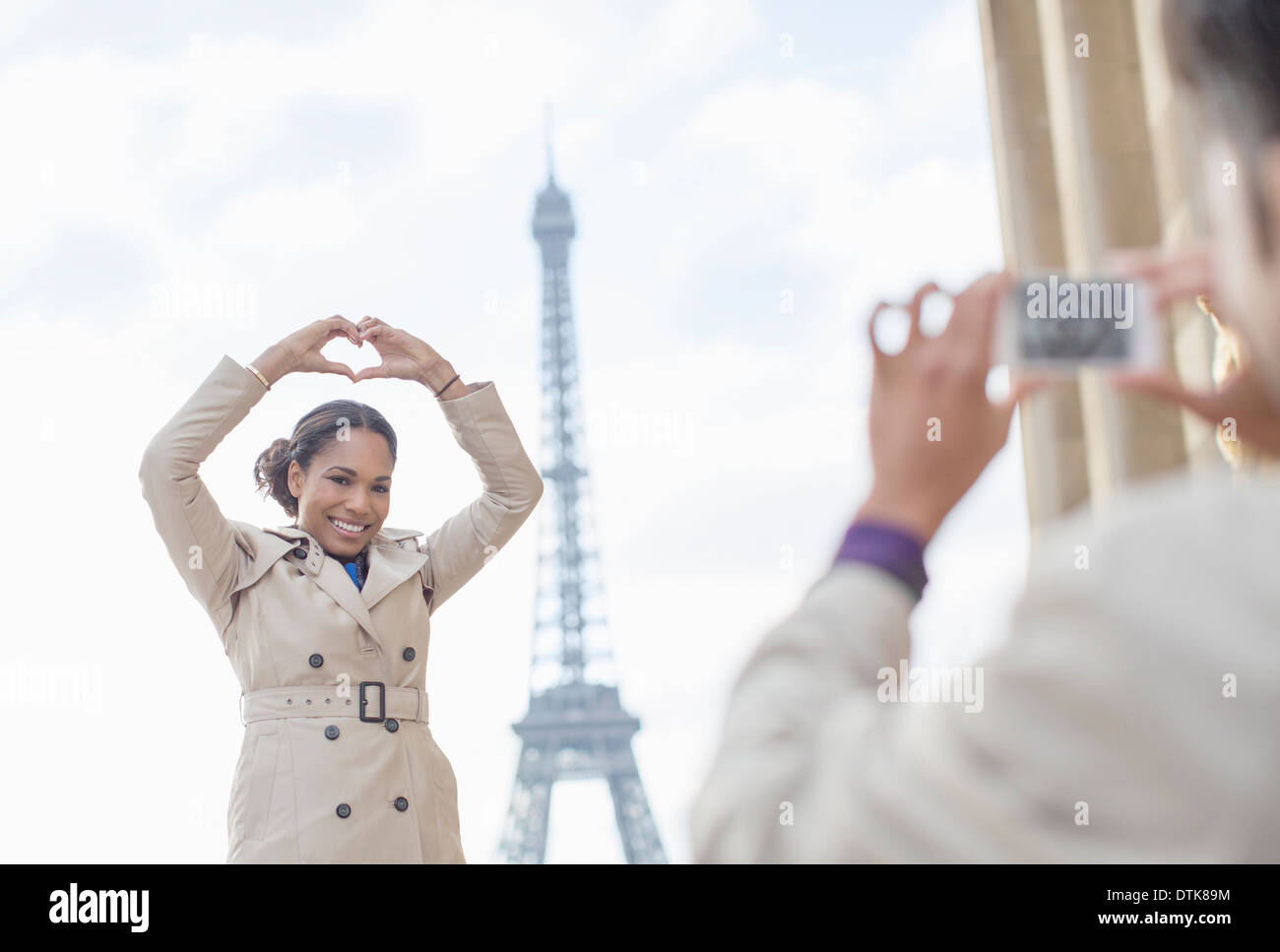 Man photographing petite amie en face de la Tour Eiffel, Paris, France Banque D'Images