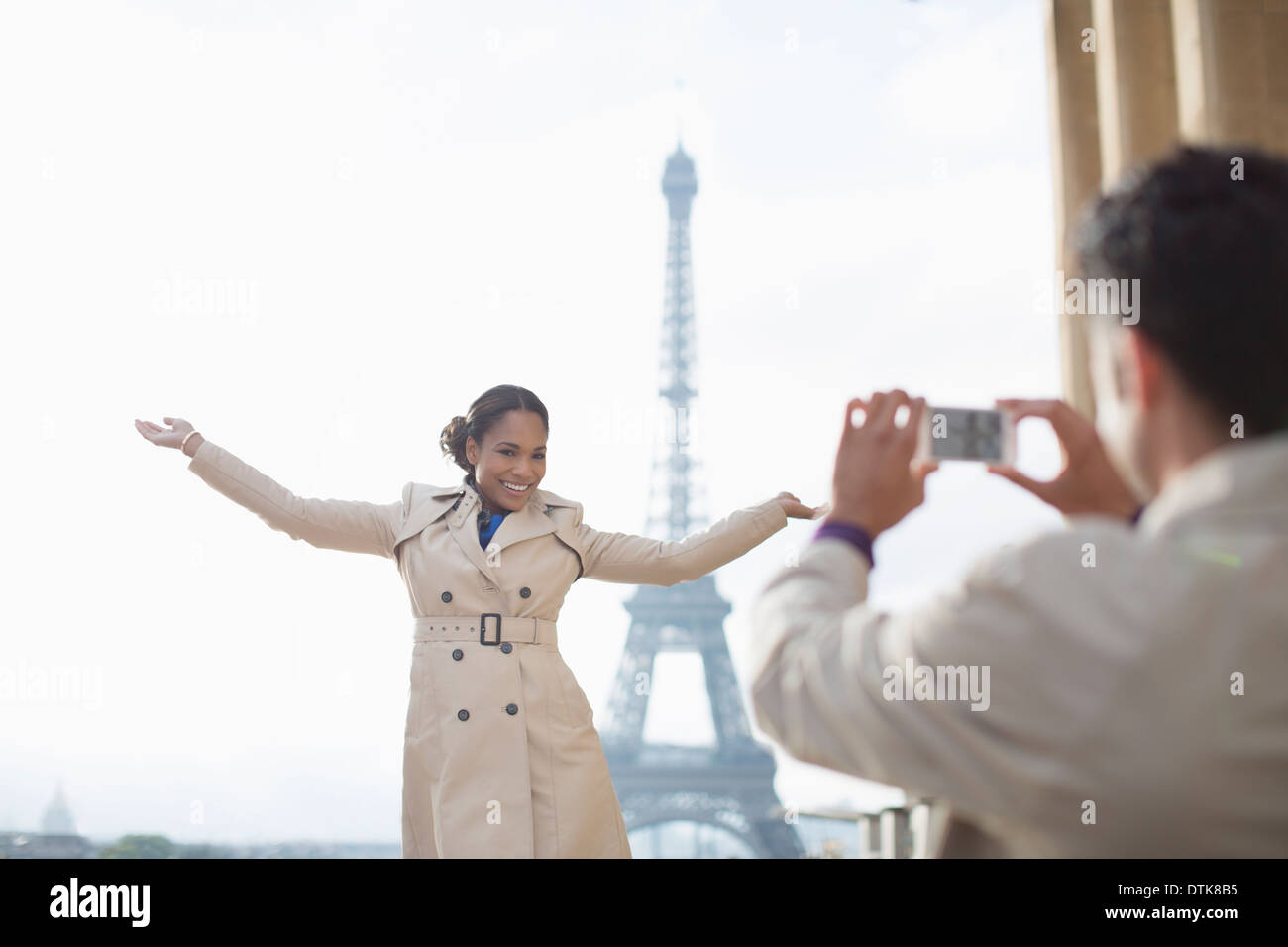 Man photographing petite amie en face de la Tour Eiffel, Paris, France Banque D'Images