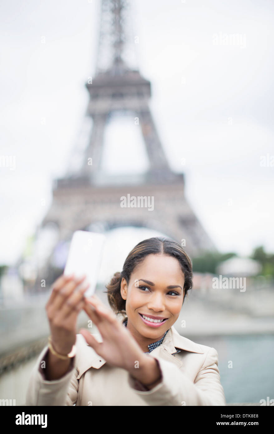 Woman taking self-portrait en face de la Tour Eiffel, Paris, France Banque D'Images
