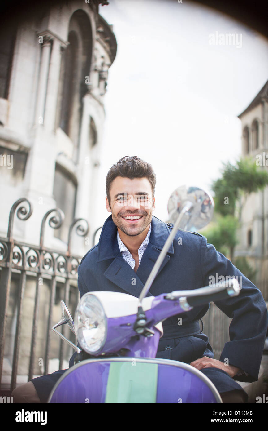 Homme assis sur un scooter on urban street Banque D'Images