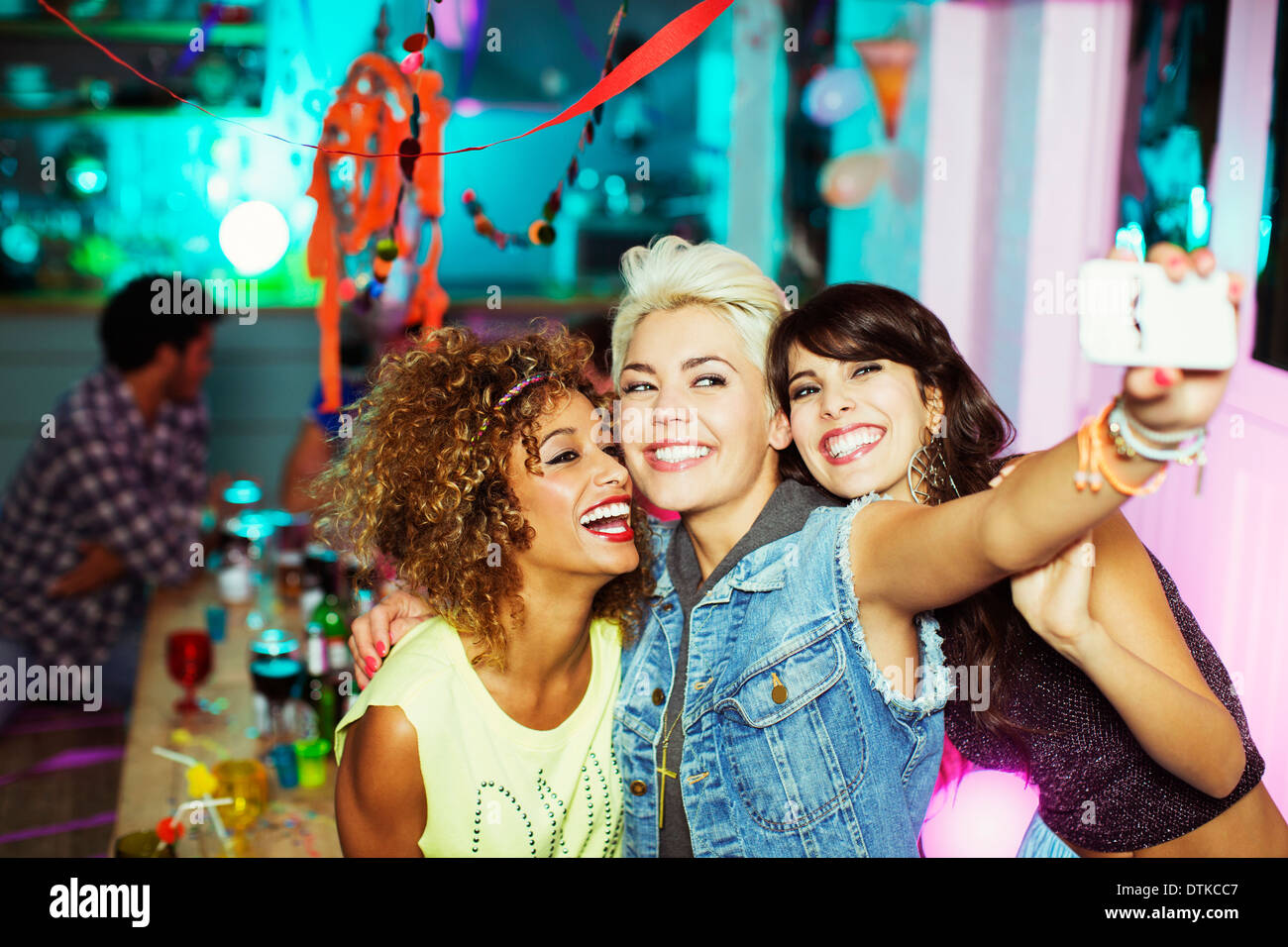 Women Taking self-portrait with camera phone at party Banque D'Images