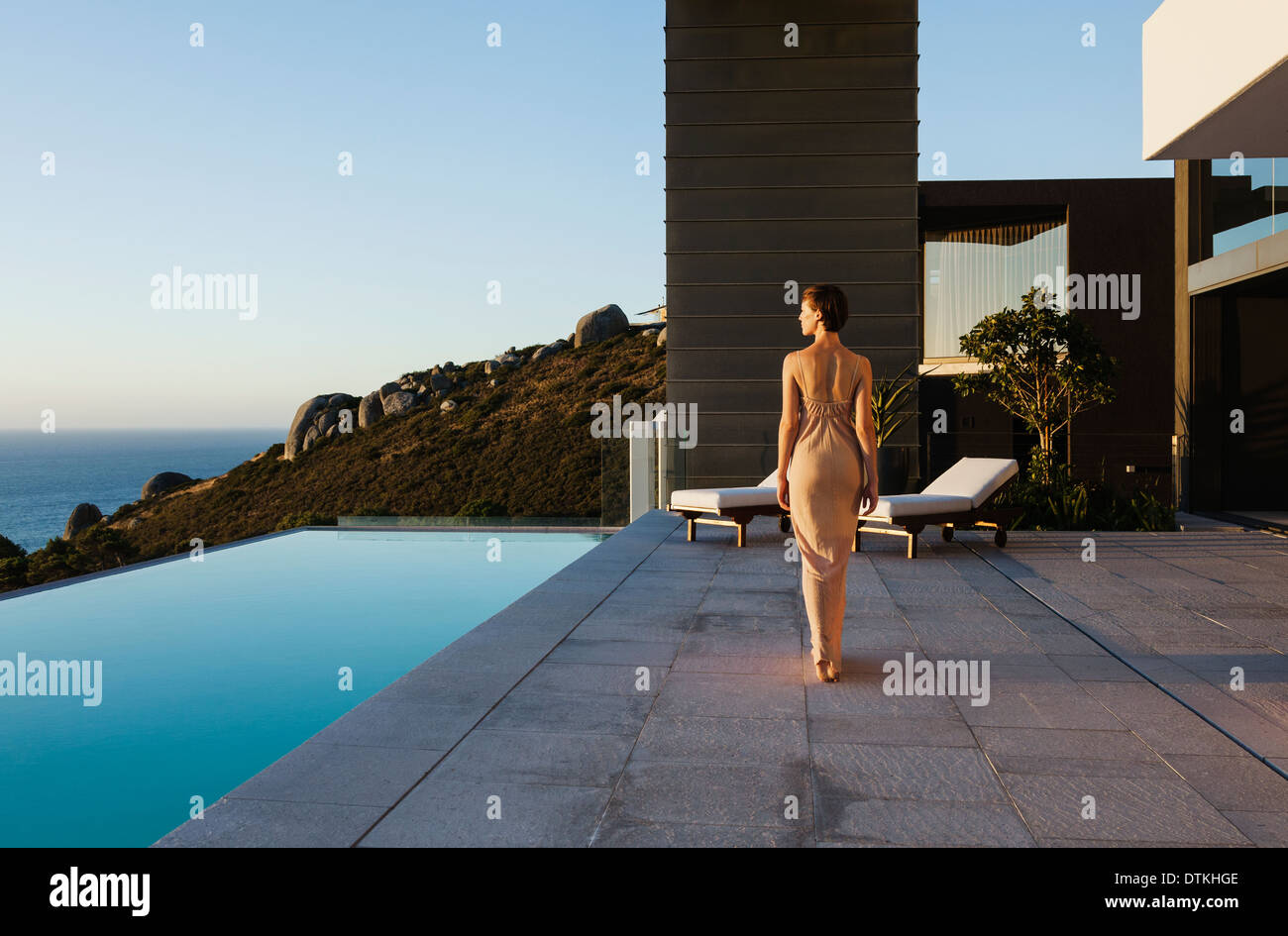 Robe femme en marchant le long d'une piscine à débordement donnant sur l'océan Banque D'Images