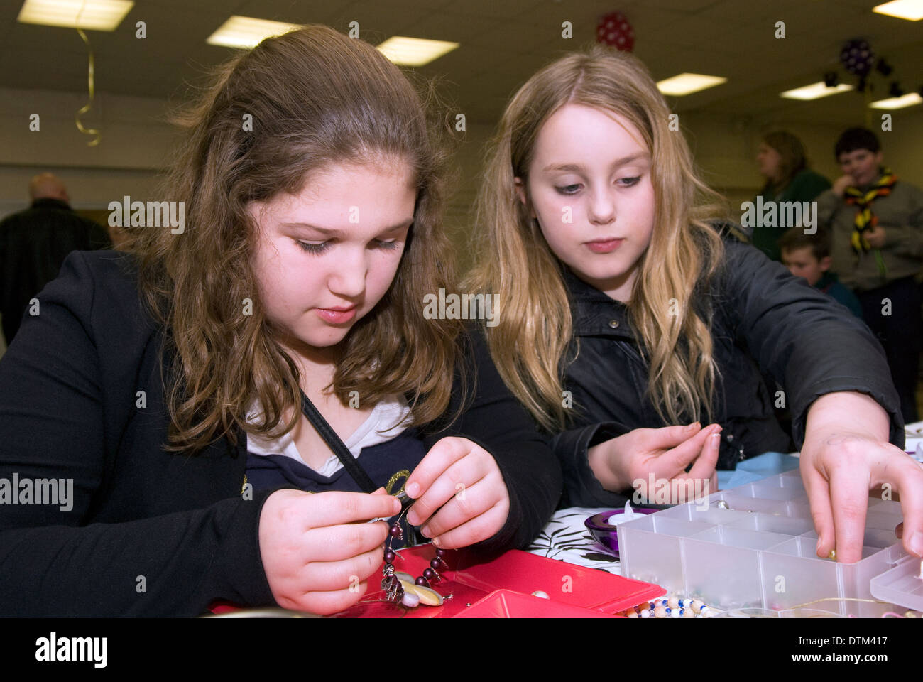 2 filles (11 ans) à un événement jeunesse l'apprentissage de la bijouterie d'encourager le développement personnel et l'engagement communautaire Banque D'Images