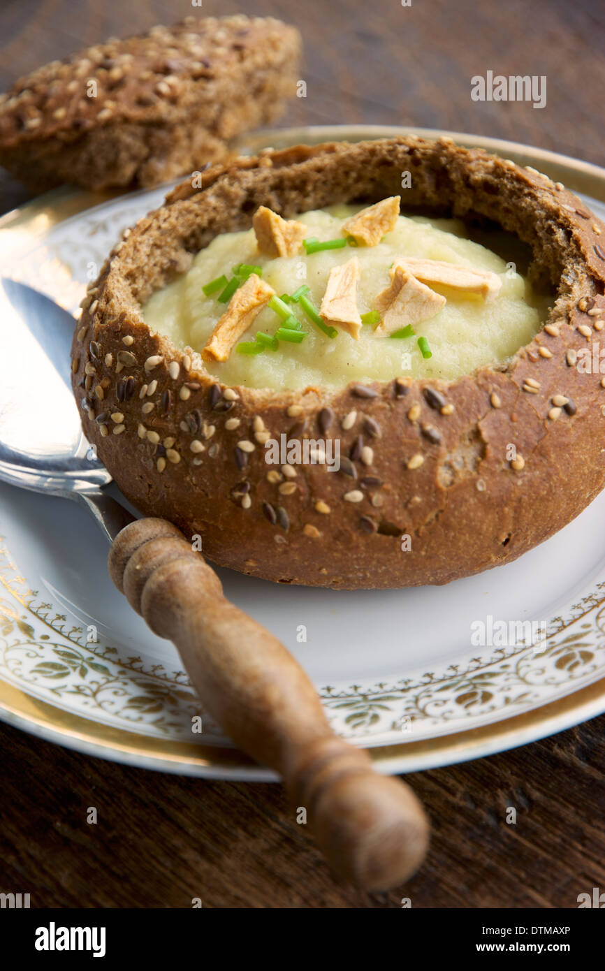 Soupe de panais pomme dans un bol de pain, garnie de morceaux de pommes séchées et la ciboulette. Banque D'Images