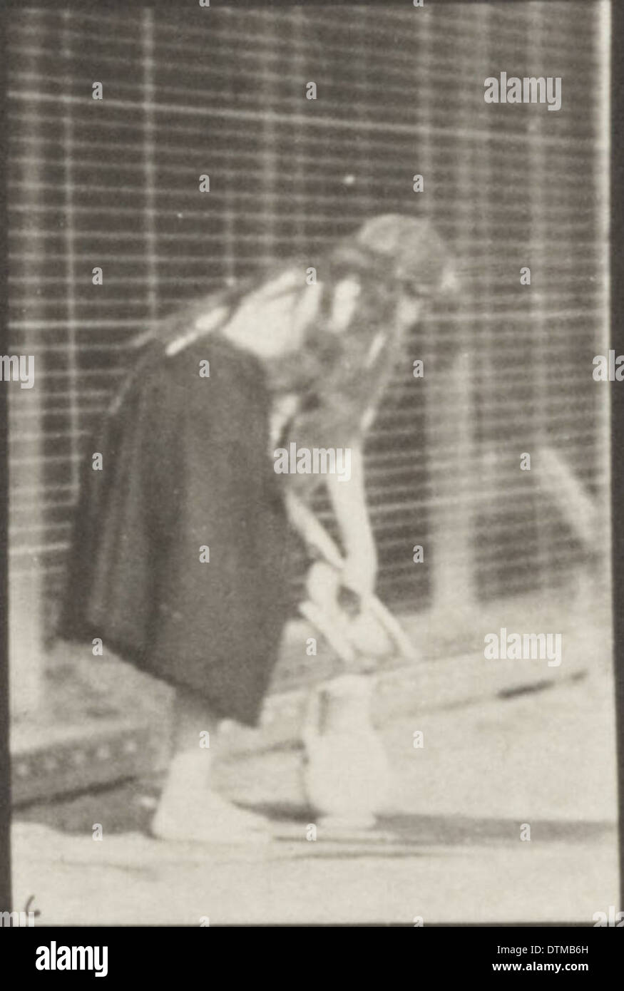 Une femme dans une robe longue soulève et vide un bassin d'eau tout en se retournant dans une pose gracieuse. Banque D'Images