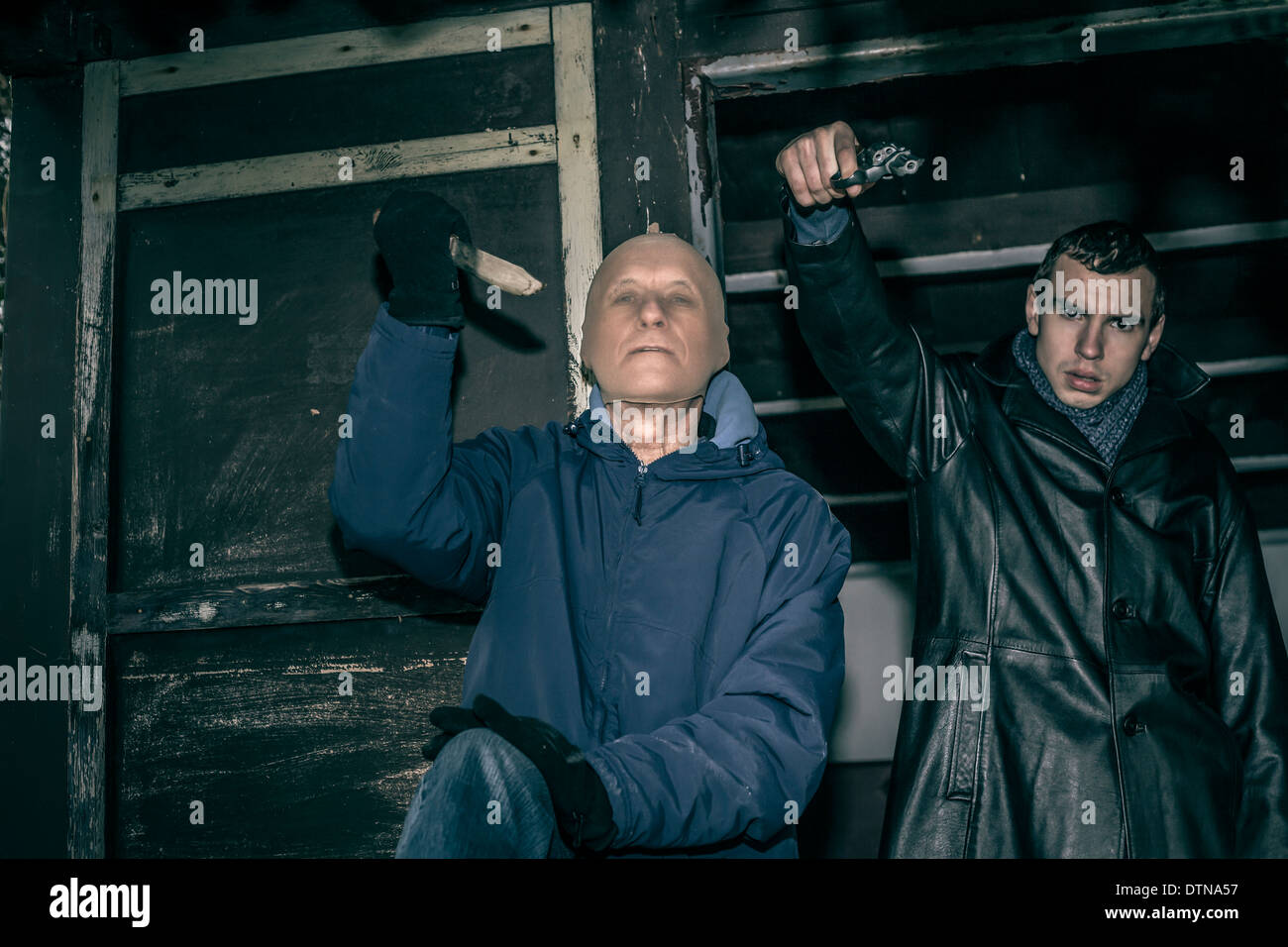 Deux hommes armés dangereux pointant avec des armes et de l'article dans la vieille cabine sombre. Banque D'Images