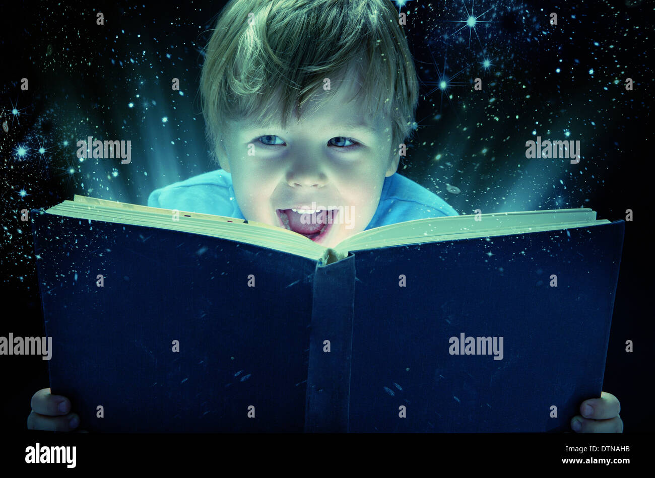 Petit garçon riant avec le vieux livre de magie Banque D'Images