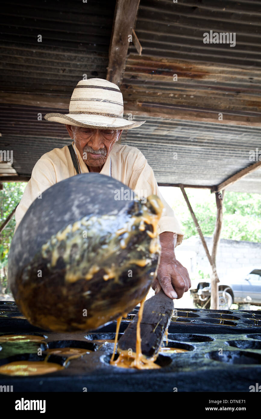 Verser le jus chaud homme panaméen à partir de la canne à faire Raspadura, près de Penonome, Province de Cocle, République du Panama. Banque D'Images