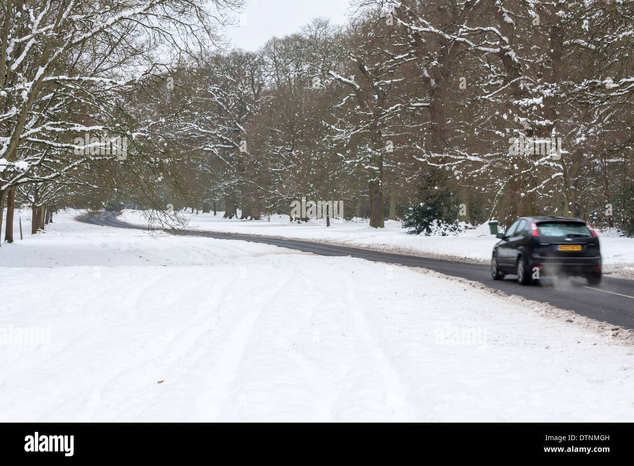 Voiture conduit le long d'une route de campagne près de Bucklebury vide dans la neige, des conditions hivernales. Berkshire, England, GB, UK Banque D'Images