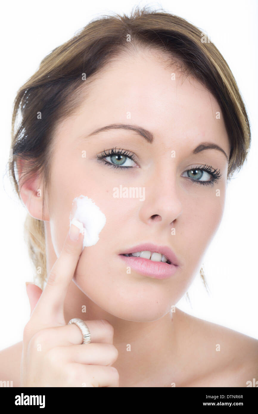 Attractive young woman applying crème hydratante Banque D'Images