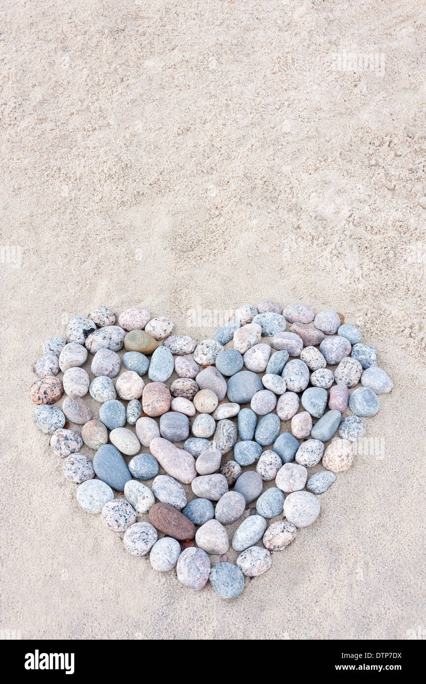 Cœur fait de pierres rondes colorées sur sand at beach Banque D'Images