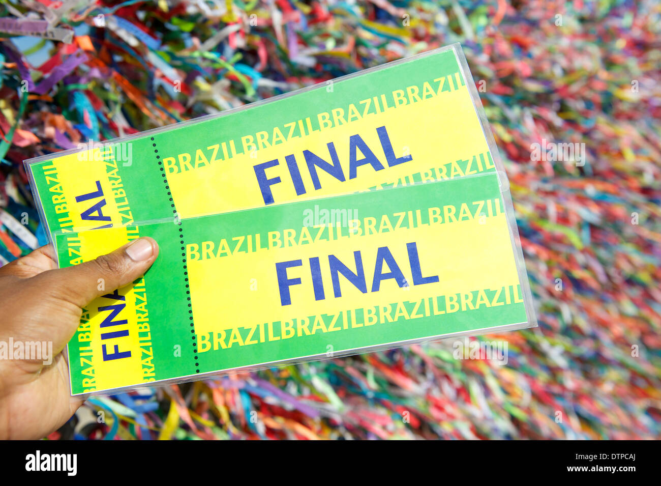 Main tenant final billets en face de fond de rubans colorés souhaite lembranca brésilien Banque D'Images