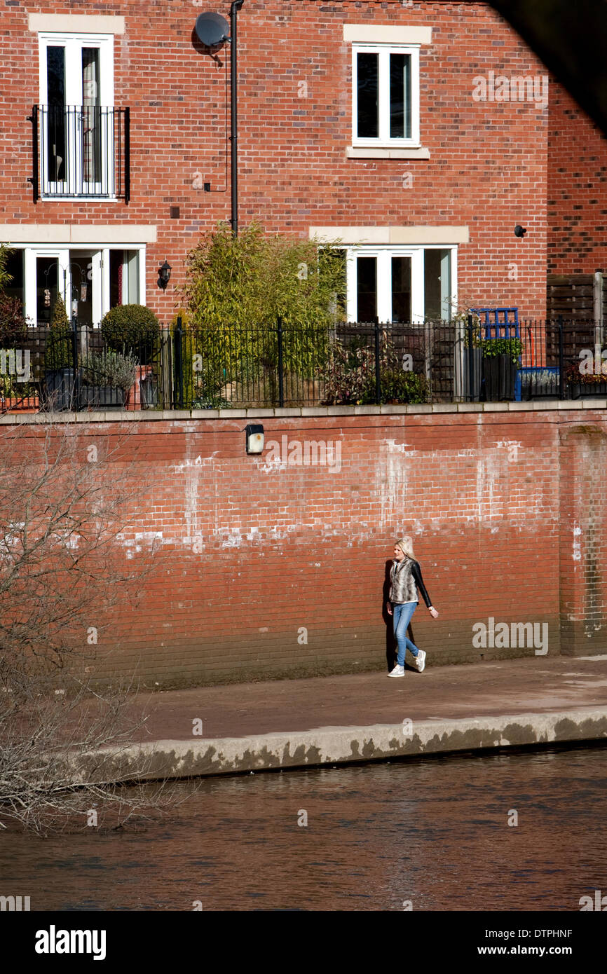 Shrewsbury, Shropshire, au Royaume-Uni. Samedi 22 février 2014. Une fille va pour une promenade le long du sentier boueux à côté de la rivière Severn. C'est la première fois que le sentier est accessible depuis qu'il a été inondé. Le plus haut niveau de l'eau durant l'inondation est indiqué par la partie supérieure de la patch humide, juste au-dessus de sa tête le long du mur. Malgré les sévères averses en février, l'excellente défense de Shrewsbury en sorte que beaucoup de foyers et d'entreprises ne sont pas inondées. Crédit : Richard Franklin/Alamy Live News Banque D'Images