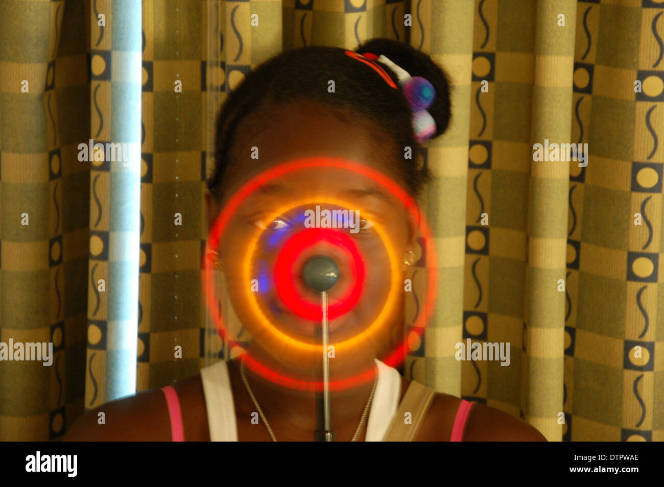 Portrait d'une jeune fille afro-antillaise avec une roue tournante jouet allumé de couleur Banque D'Images