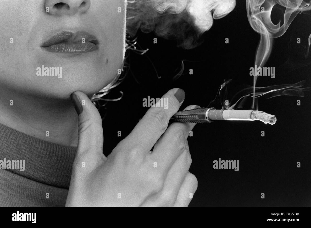 Un gros plan d'une femme qui fume une cigarette à l'aide d'un porte-cigarette Banque D'Images