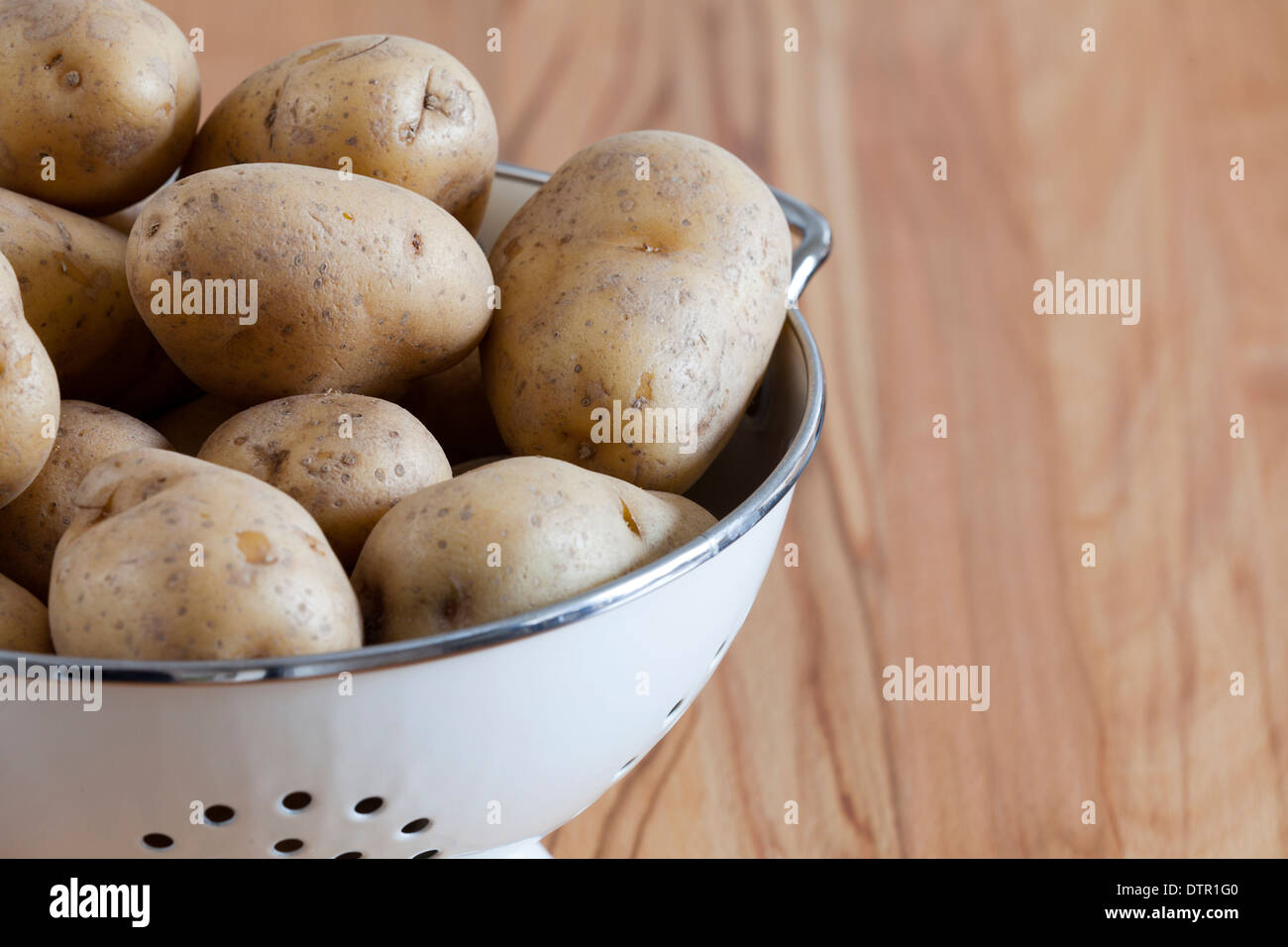 Close up de matières premières pommes de terre dans une passoire, avec l'exemplaire de l'espace sur le côté droit de l'image Banque D'Images