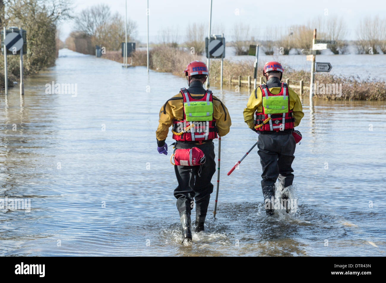 Burrowbridge, UK. Feb 22, 2014. Le Somerset les agents de service d'incendie et de sauvetage patauger dans l'eau de l'inondation à Burrowbridge le 22 février 2014. Vêtus de gilets et échassiers, deux hommes à pied le long de la chaussée de l'A361, aujourd'hui totalement submergé par les crues au cours de l'inondation la plus lourde dans l'histoire vivante sur le Somerset Levels. Ils sont à l'aide de mesure afin de déterminer la profondeur de l'eau le long du chariot qui s'élève actuellement à 1,1 mètres à ce carrefour. Credit : Nick Cable/Alamy Live News Banque D'Images