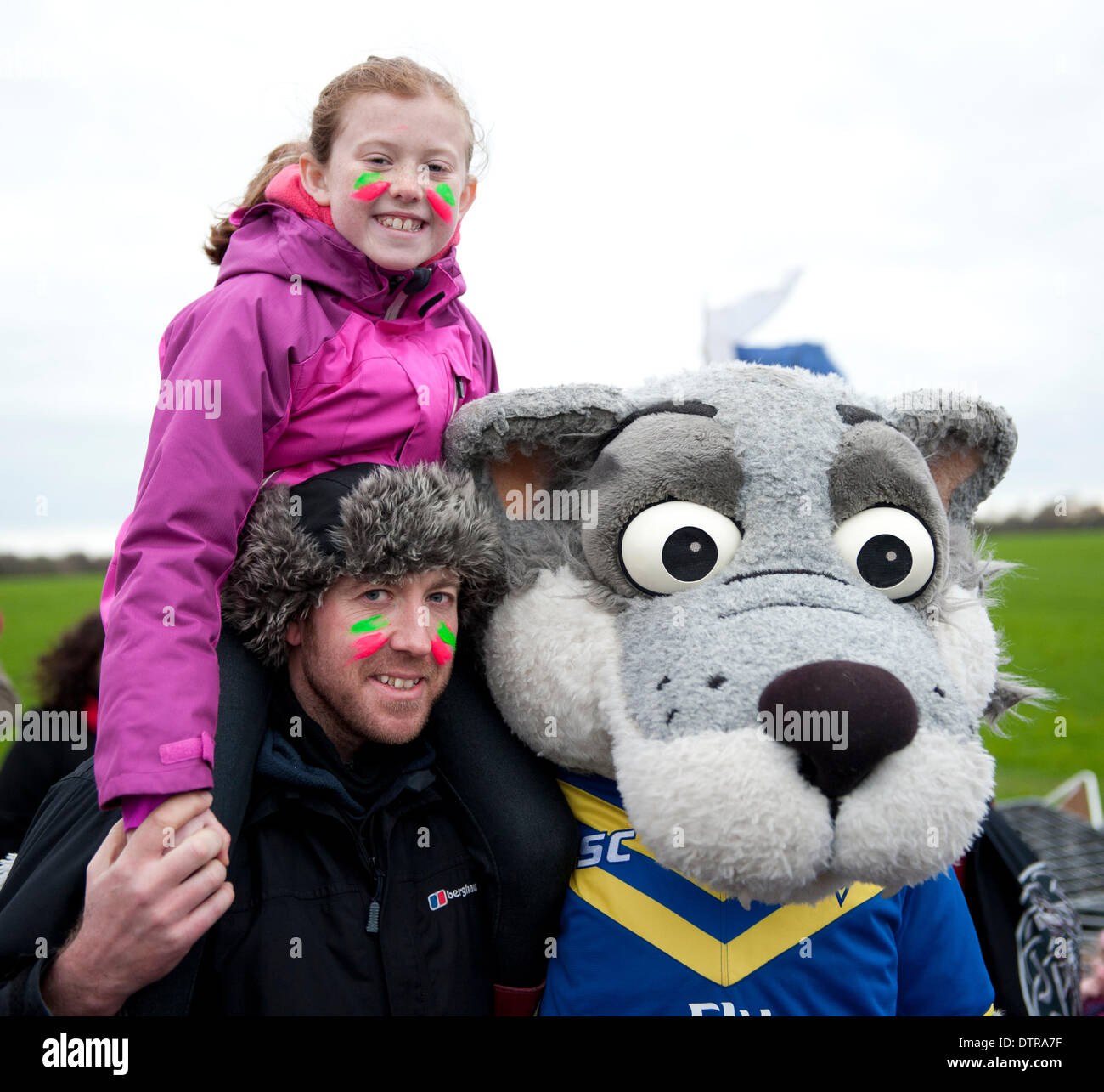 Barton Moss, Salford, Royaume-Uni. Dimanche 23 février 2014. La Warrington Wolves Rugby League mascot "Wolfie" pose pour une photo avec un père et sa fille à Barton Moss. Des manifestants anti-fracking sur Barton Moss près de Manchester continuer leur campagne pour un troisième mois contre le forage d'exploration à proximité du site Barton de l'IGas. La peur des militants le processus de fracturation hydraulique pourrait être dangereux pour l'environnement, et mener à l'empoisonnement de l'approvisionnement en eau et d'une contamination de l'atmosphère. Credit : Russell Hart/Alamy Live News. Banque D'Images