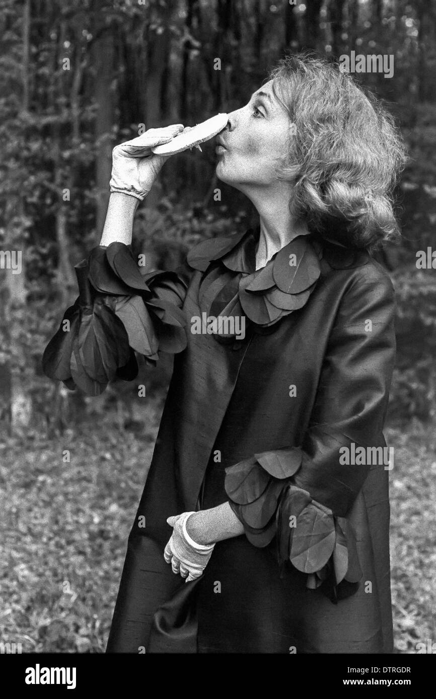 Modèle de mode des années 60 avec manteau noir tenant un champignon Banque D'Images