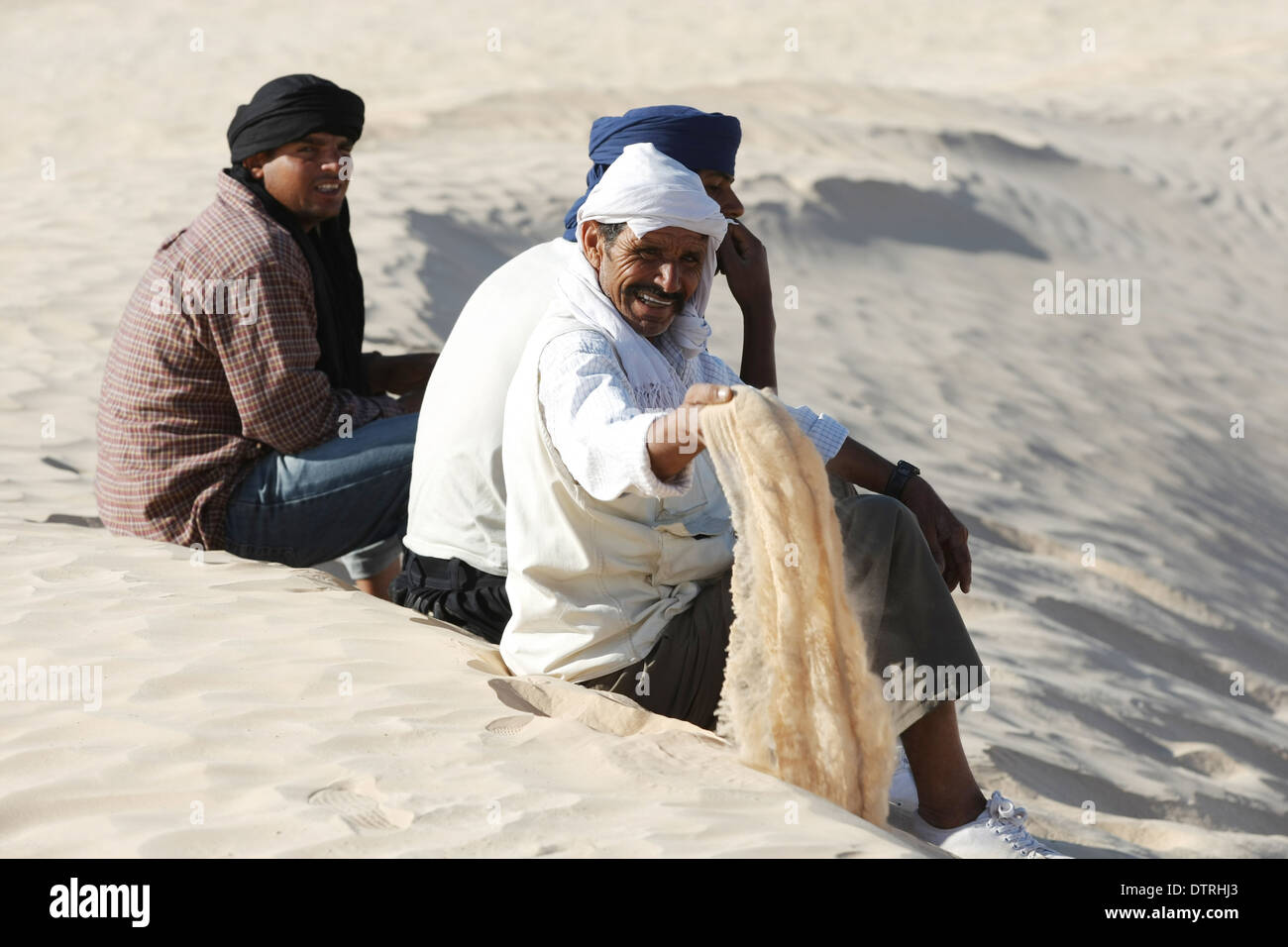 Les bédouins se reposant sur le sable au cours de la visite touristique des touristes sur des chameaux à Douz, Tunisie,Sahara. Banque D'Images