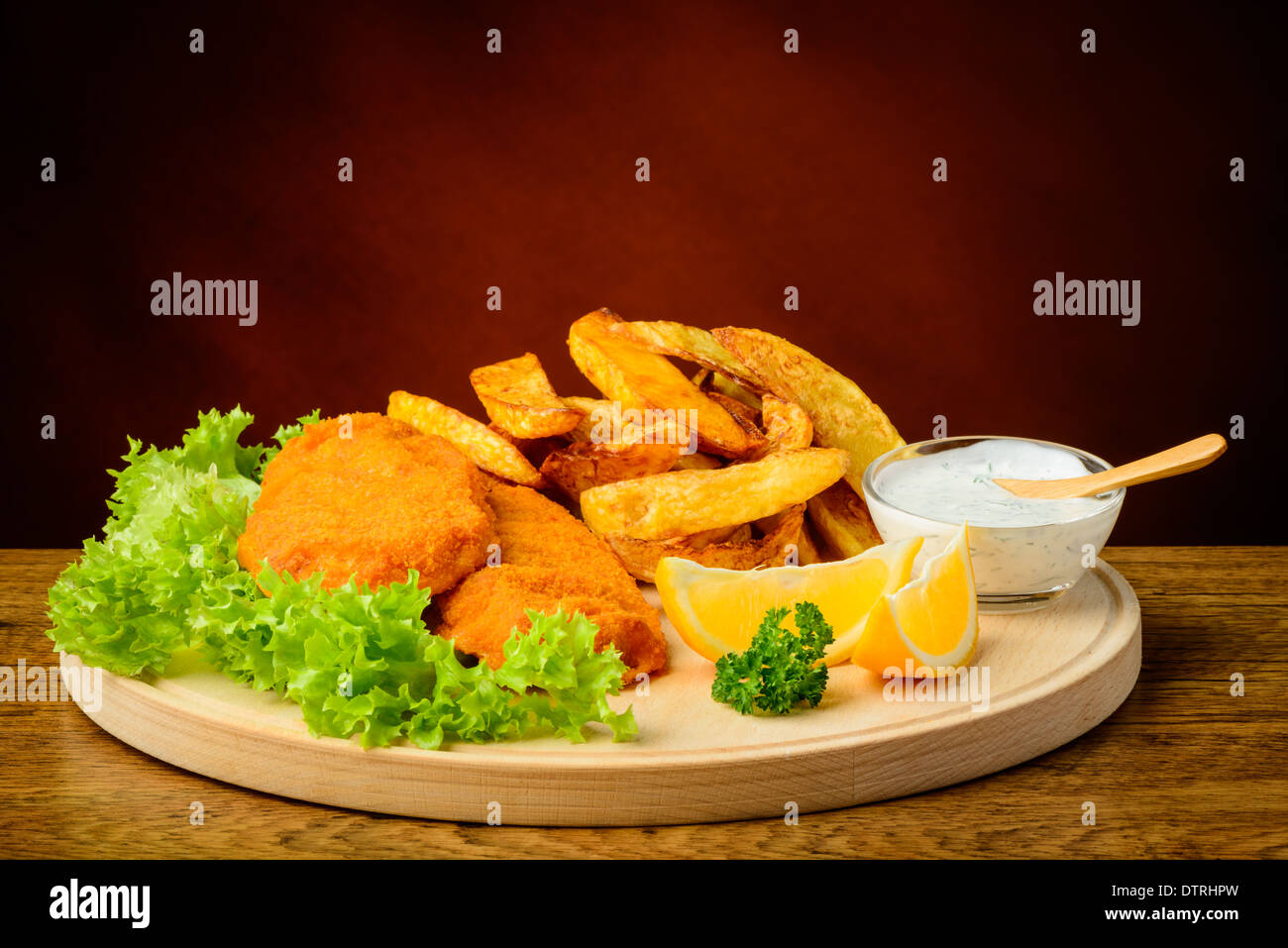 Still Life with fish and chips, citron, sauce dip sur une plaque de bois Banque D'Images