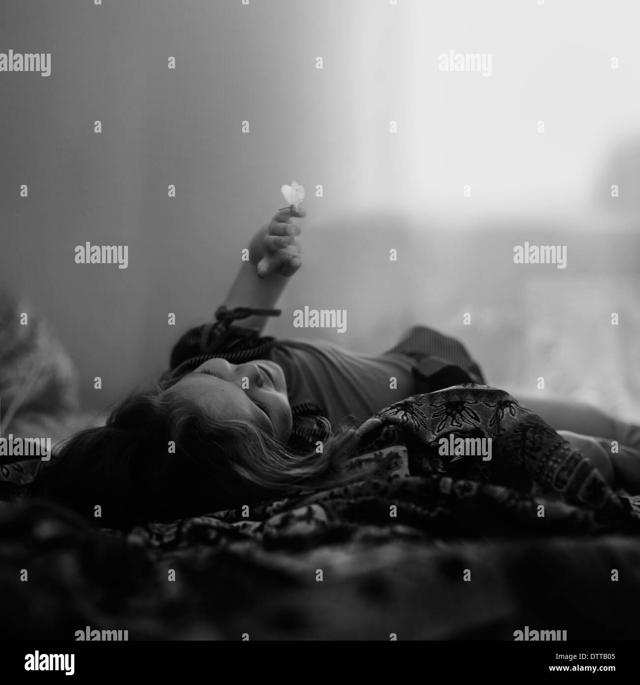 Caucasian girl laying on blanket avec papillon sur le doigt Banque D'Images