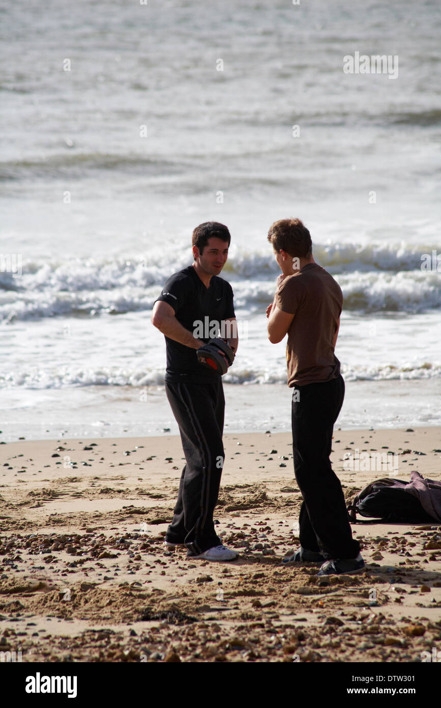 Deux hommes à l'exercice de la plage de Boscombe self défense boxe en Février Banque D'Images