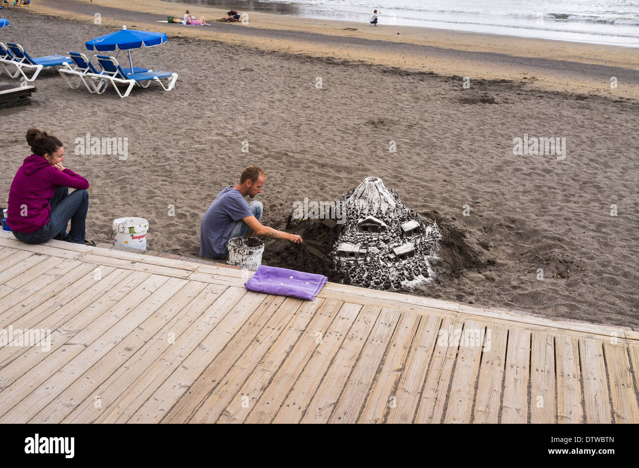 Sculpteur de sable au travail faire une montagne couverte de neige scène à la plage d'El Medano, Tenerife, Canaries, Espagne Banque D'Images