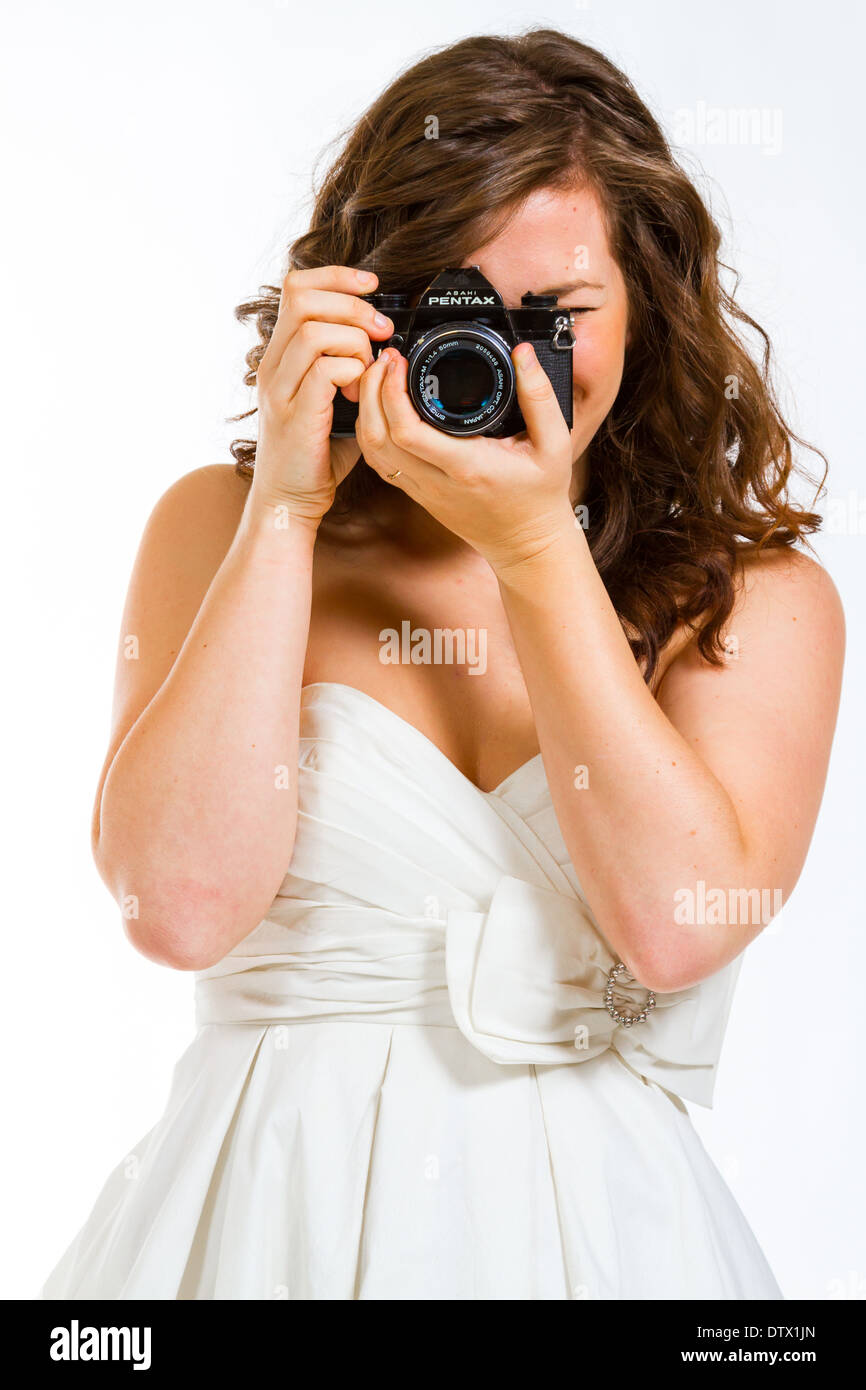 Une belle épouse tenant un appareil photo en studio contre un fond blanc. Banque D'Images