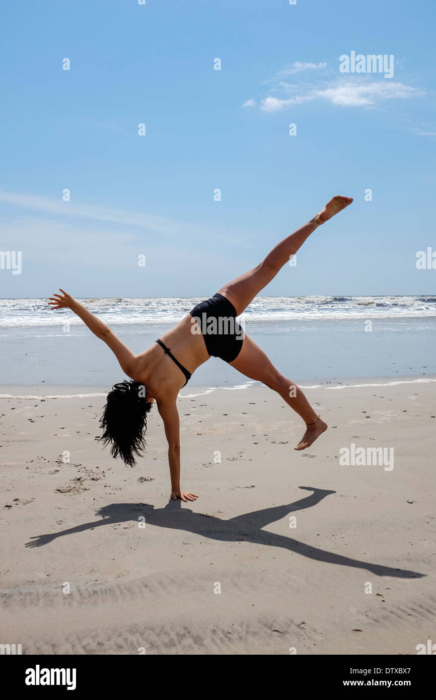 La santé de la jeune adolescente cartwheeling sur une plage Banque D'Images