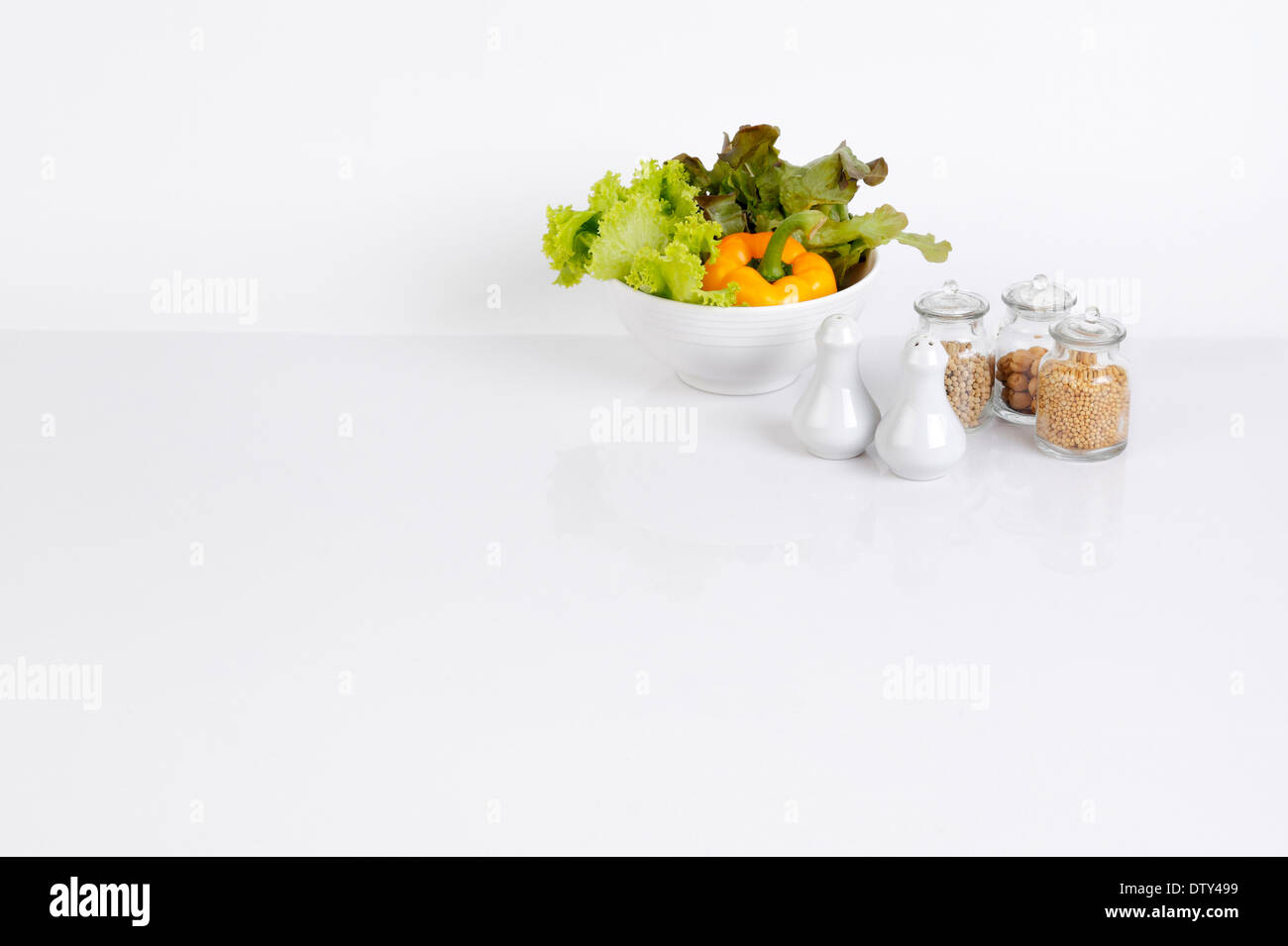 Cuisine avec arrière-plan blanc bol de légumes et l'assaisonnement de bouteilles Banque D'Images