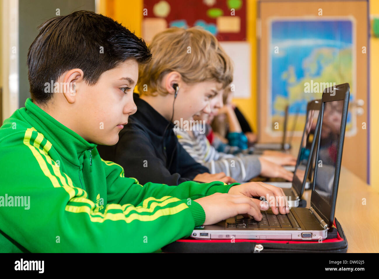 Des élèves du premier cycle du secondaire (environ 12 ans) travailler avec leur ordinateur portable dans leur classe. Banque D'Images